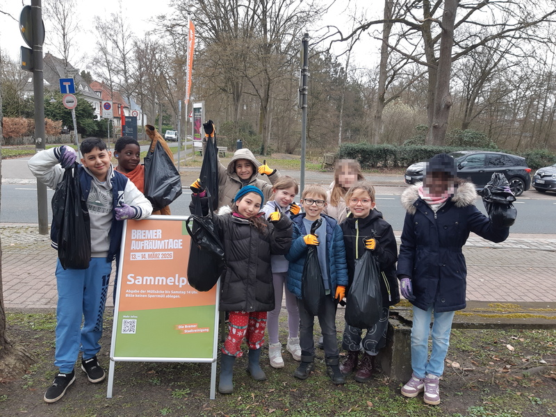 Das Bild zeigt: Alle Kinder der Klassen 2 und 3 stehen am Sammelplatz der Bremer Aufräumtage und zeigen ihre Säcke voll mit gesammeltem Müll.