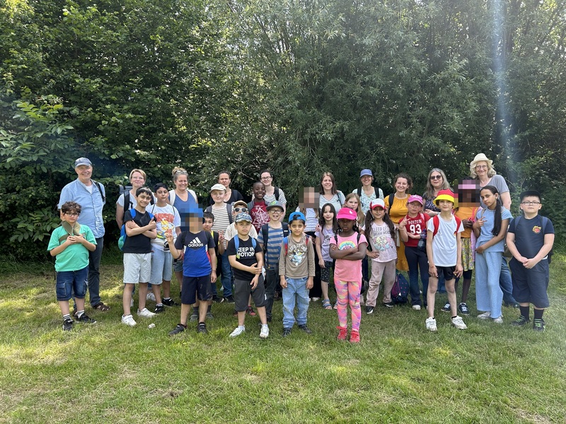 Das Bild zeigt: Alle Kinder und Lehrkräte der Klassen E, 1, 2 und 3 stehen für das Gruppenfoto bereit.